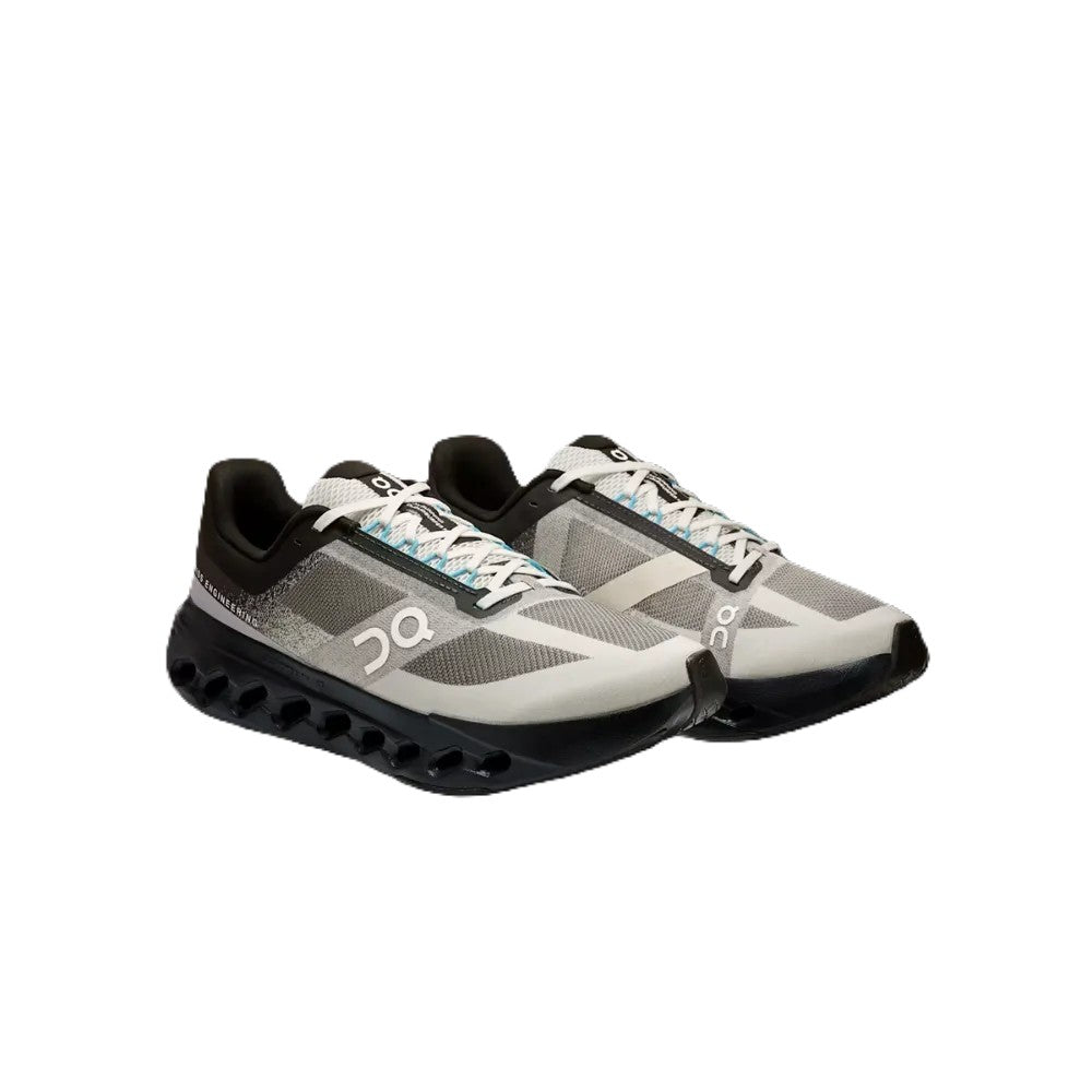 A pair of On running shoes in gray, black, and white, featuring the signature On logo on the side and a black carbon-celled sole, shown against a plain white background.