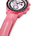 Pink Omega x Swatch Speedmaster wristwatch with a pink textured strap, black bezel, and a white dial featuring a pink cartoon character.