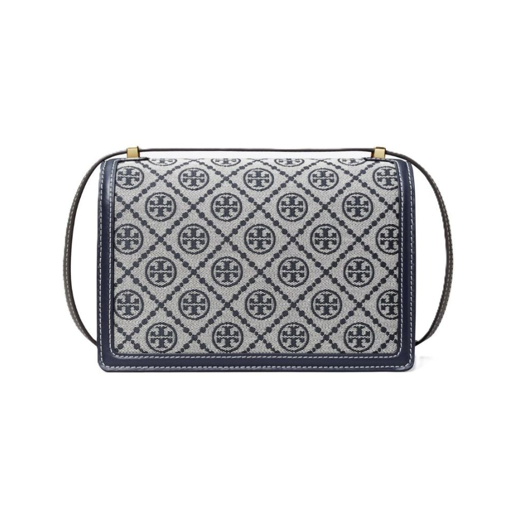 A Tory Burch shoulder bag featuring a navy blue and gray monogram patterned body, a thin dark gray strap, and gold-tone hardware on a plain white background.