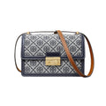 A Tory Burch handbag with a navy and white patterned canvas body, a brown leather shoulder strap, and a gold-tone turn-lock clasp, shown on a plain white background.