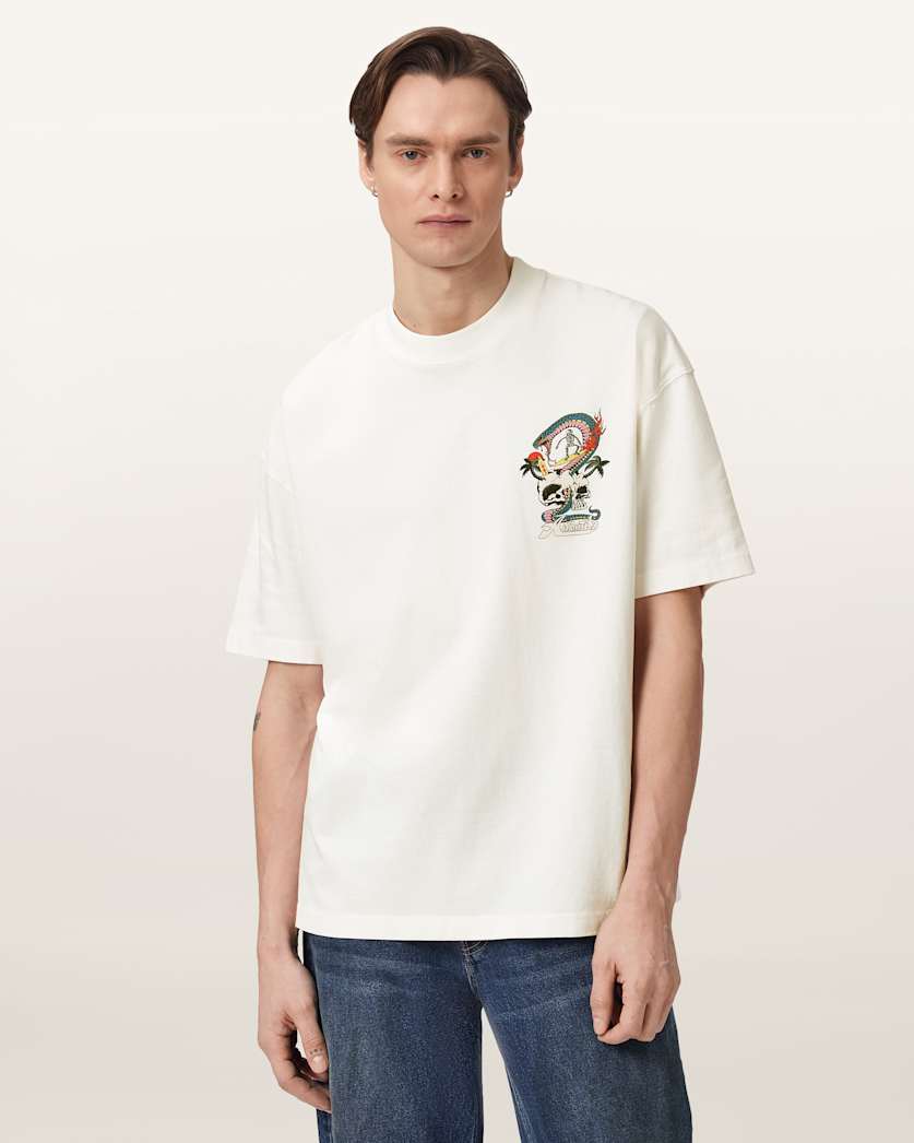 An off-white short-sleeve crewneck t-shirt featuring a colorful graphic print on the left chest with a cartoon character, rainbow, and palm trees, displayed on a clean white background.