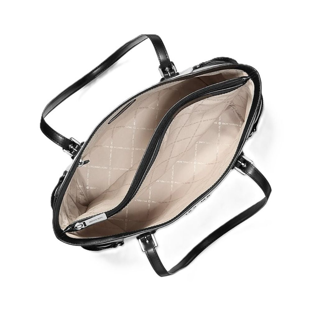 An overhead view of a black leather handbag showing its spacious interior with a beige quilted pattern lining and silver-tone hardware.