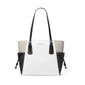 Michael Kors tote bag in white monogram canvas with black leather trim, double shoulder straps, and black side pockets, shown on a plain white background.